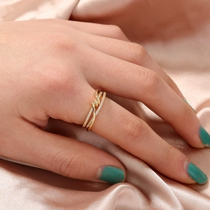 Detailed view of a gold knot ring with pave-set cubic zirconia on a silk background