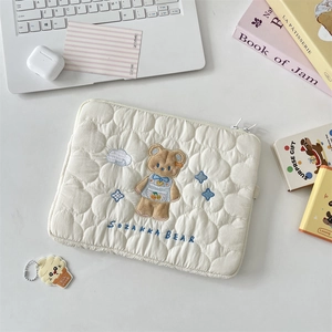 Detalle del patrón de nubes acolchadas y bordado de oso en la funda de ordenador