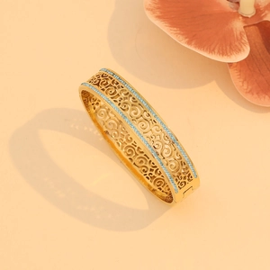 Detailed close-up of golden stainless steel cuff with turquoise stones and hollow carving