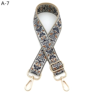 Close-up of jacquard floral shoulder strap with gold metal lobster clasps and buckle