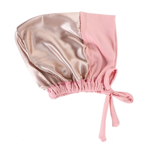 Detail of satin hair bonnet featuring champagne gold and pink contrast fabric and ties