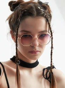 Close-up of golden octagonal sunglasses with gradient pink lenses on a female model