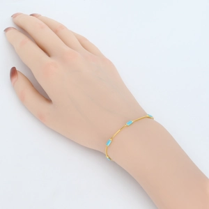 Close-up of minimalist gold chain bracelet with five rectangular turquoise stones on hand
