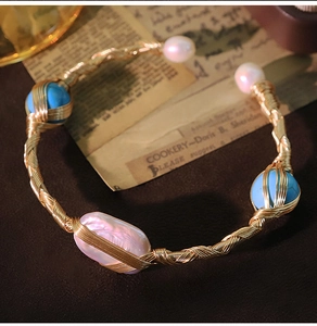Detailed close-up of handmade gold wire-wrapped bracelet with baroque pearls and blue stone