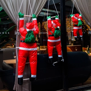 Vista dettagliata di tre Babbo Natale che salgono su una scala di corda alla finestra