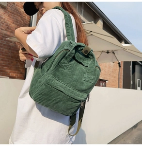 Sac à dos en velours côtelé vert pour femme porté dans un cadre extérieur élégant