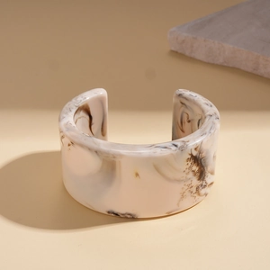 Close-up of retro marbled resin cuff bracelet with cream and brown textures