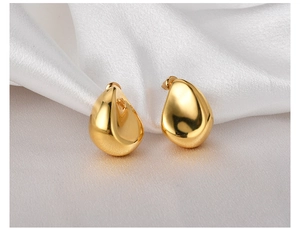 Detailed close-up of 18K gold-plated teardrop earrings on elegant white silk background
