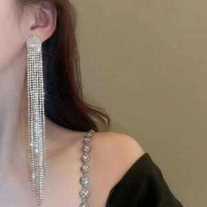 Close-up of sparkling long tassel earrings with rhinestones on a female model