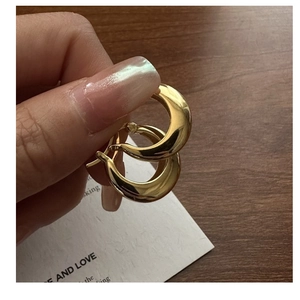 Detailed view of hand-held gold thick U-shaped crescent sterling silver hoop earrings