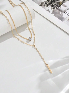 Detail of gold Y-shaped layered necklace with teardrop gemstone and vertical bar pendant