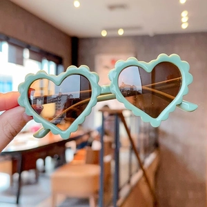 Kids heart shaped sunglasses with mint green wavy frames and dark lenses for fashion wear