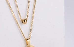 Close-up of a double-layered gold plated necklace with ball and heart pendants