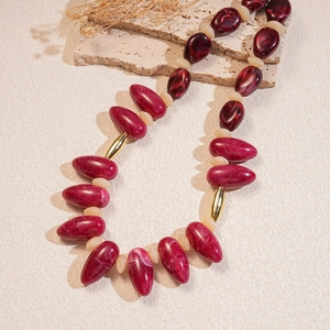 Acrylic marbled bead necklace with dark red oval charms and gold accents on stone base