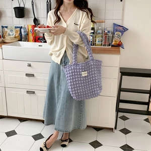 Detail of light purple bubble textured tote bag with rectangular white brand label
