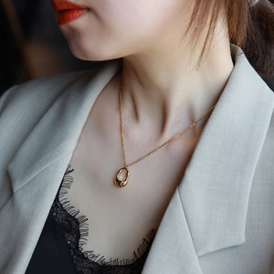 Minimalist gold hollow teardrop pendant necklace worn by model on a light suit