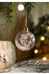 Detail of 8cm glass Christmas ball with snowman pattern hanging on pine branch