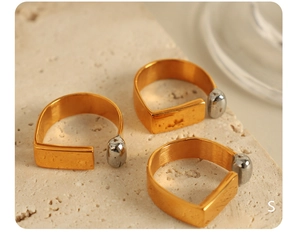 Three irregular U-shaped gold plated titanium rings with silver ball details on stone