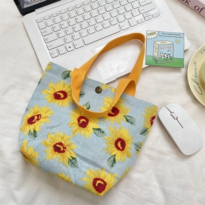 Flat lay of light blue sunflower tote bag with laptop and chic lifestyle accessories