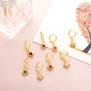 Detail view of gold hoop earrings with multi-colored star pendants on a pink fabric background