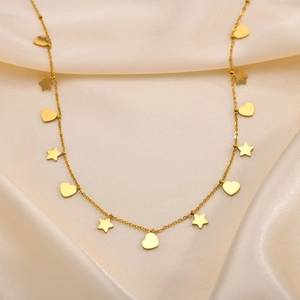 Dettaglio della collana dorata con ciondoli a stella e cuore su elegante seta beige
