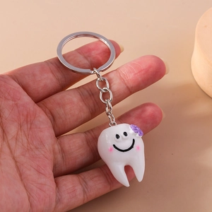 Simpatico portachiavi a forma di dente con fiore viola e faccina sorridente in metallo