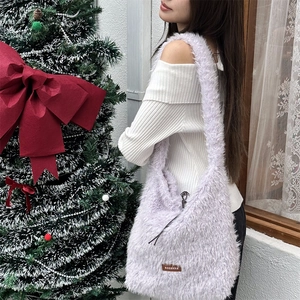 Close-up of lilac plush tote bag with brown leather logo tag in a cozy winter setting