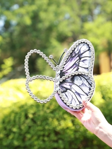 Close-up of butterfly evening bag with purple prints and sparkling rhinestones