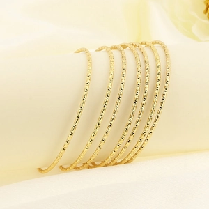Set of 7 gold-toned faceted thin bangle bracelets in a minimalist luxury style