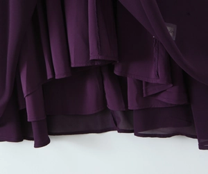 Detail of the multi-layered chiffon hemline on a deep purple halter neck midi dress