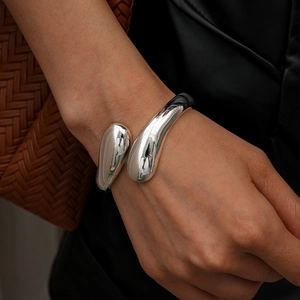 Close-up of geometric silver crossover open bangle with polished metallic fluid design
