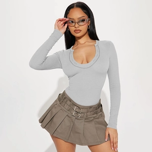 Detail of grey ribbed knit long sleeve bodysuit and khaki pleated mini skirt with belt