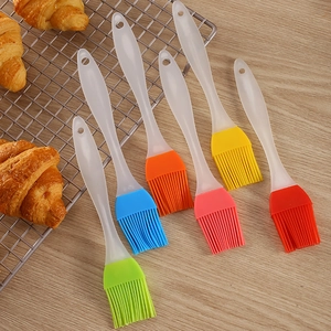 Set of 7 colorful silicone basting brushes with clear handles on a rustic baking setup