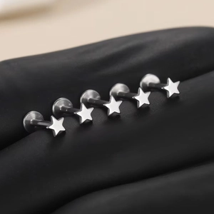 Macro shot of five silver F136 titanium star-shaped flat back studs on black surface