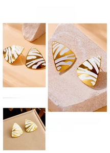 Macro detail of geometric triangle earrings with white enamel and golden metal borders
