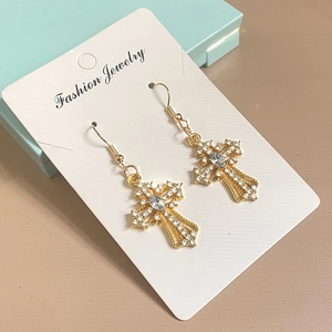 Close-up of golden cross drop earrings with sparkling zircon crystals on jewelry box