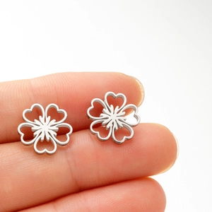 Gros plan sur les boucles d'oreilles fleurs ajourées en argent poli portées à la main