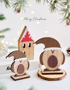 Detailed view of wooden Christmas desk ornaments featuring penguins and a small red cottage