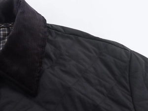 Detail of black quilted nylon jacket featuring corduroy collar and plaid lining