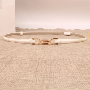 Detail view of a slim white leather belt with a golden U-shaped buckle on a linen background