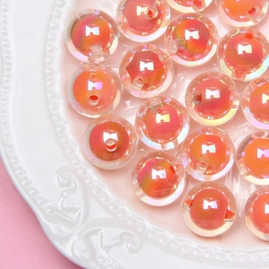 Close-up of DIY iridescent orange-pink beads with a hole on a white embossed plate