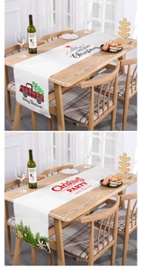 Detail of Christmas table runners with red truck and festive holiday greetings on linen fabric