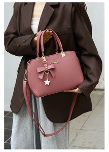 Pink handbag styled with brown blazer, featuring bow decor and golden metal logo