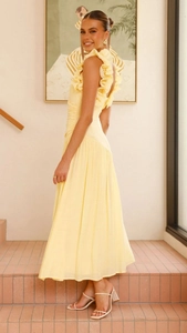 Détails de la robe jaune sans manches avec des plis élégants et des ornements volantés