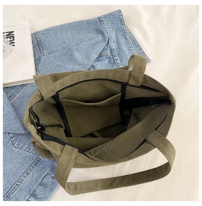 Detail view of military green canvas tote bag interior showing the zipper and inner pocket