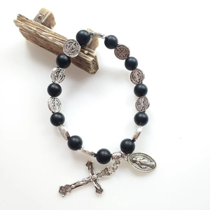 Elastic volcanic stone bead bracelet with silver Benedictine cross and medals on wood