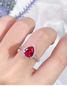 Detail of a pear-shaped ruby ring in S925 silver worn on hand against a white background