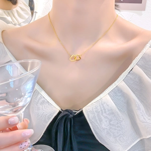 Elegant 18k gold plated double heart necklace with crystals on a model holding a glass