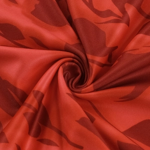 Detailed close-up of red camouflage knit fabric texture and soft draped material