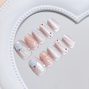 Light blue cat-eye press-on nails with 3D floral accents and shimmering rhinestones